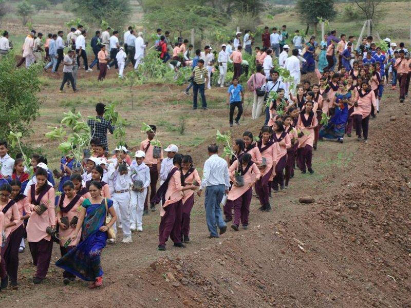Students and volunteers carrying saplings for community planting